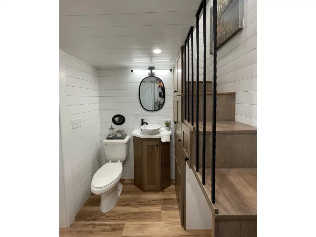 Bathroom showing commode, sink, and stairs to loft