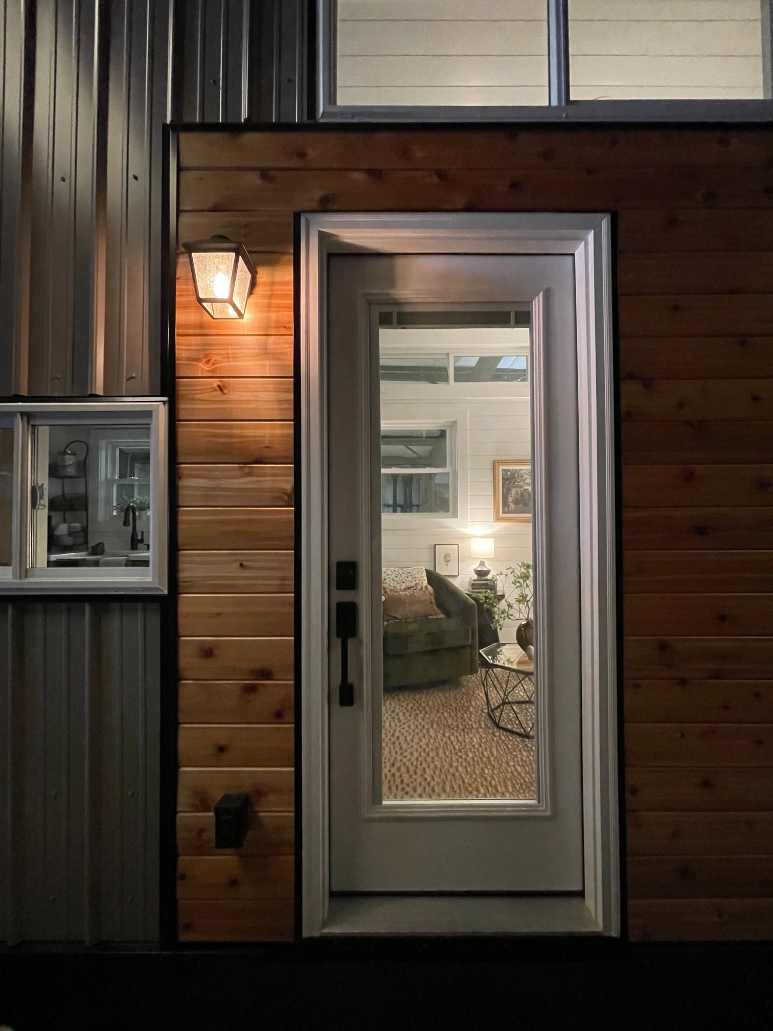 Door to tiny home at night with welcoming inside lights